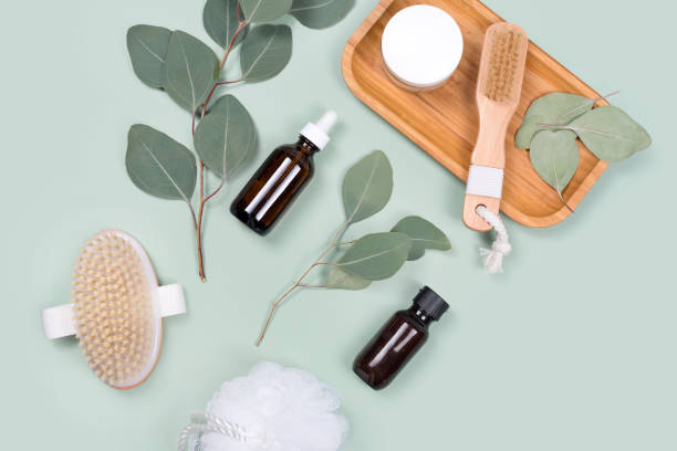 istock Essential oils, facial creme container and massage brushes with natural eucalyptus leaves on green background. Beauty products, massage tools, facial skin care, spa beauty treatment concept. Flat lay 1307883725
