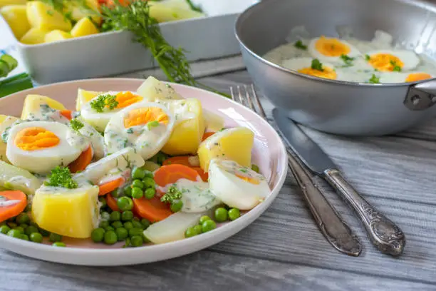 homemade vegetarian family dish with boiled eggs, vegetables, potatoes and a delicious herb bechamel sauce served on a plate with knife and fork. Ready to eat
