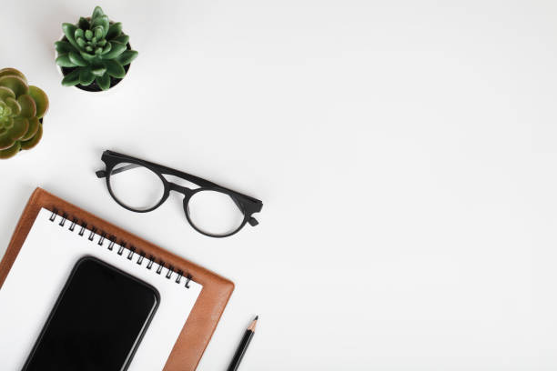 istock office table desk, workspace with mobile phone, notebook, pencil, green plant and eyeglass. Business background. Flat lay, top view. copy space 1307888397