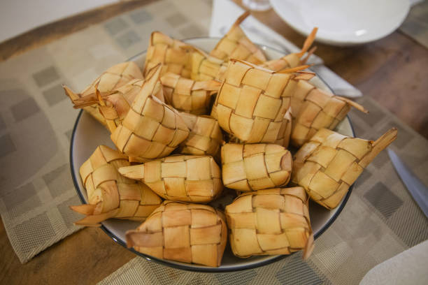 Indonesian Traditional Rice Dish Ketupat Close-up shot stack of ketupats on glass bowl above dining table at home during ramadan. traditional malaysian food stock pictures, royalty-free photos & images