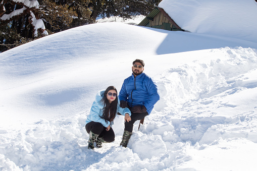 Couple in warm clothing spending leisure time on snow during ski holiday