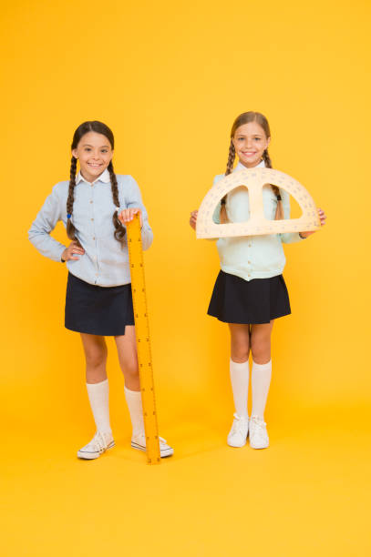 istock Where pupils achieving excellence together. Cute pupils holding protractor and ruler on yellow background. Little pupils with mathematical instruments ready for maths. Adorable pupils back to school 1307891936