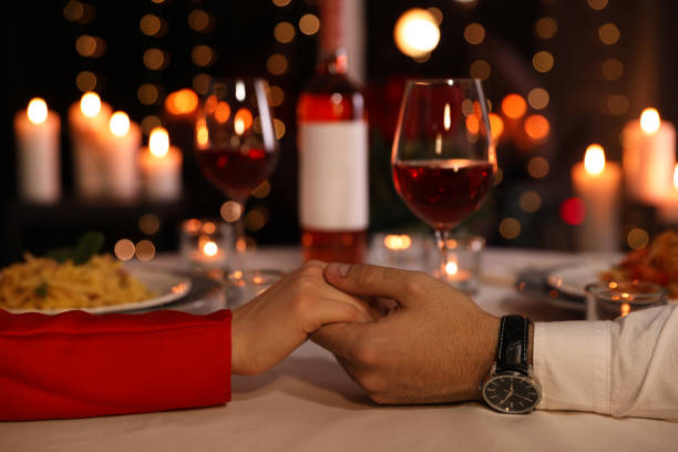 Couple holding hands together at table during romantic dinner in restaurant, closeup Couple holding hands together at table during romantic dinner in restaurant, closeup candle light dinner stock pictures, royalty-free photos & images