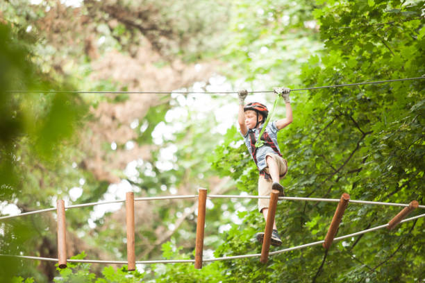 istock Low Angle View Of Boy Climbing On Rope Against Trees 1307893340