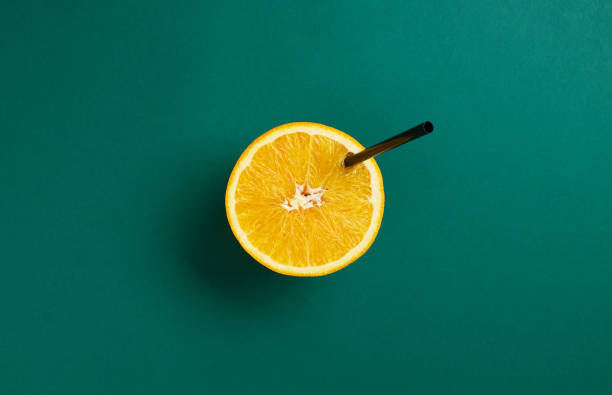istock half of fresh ripe orange fruit with black straw 1307894494