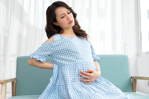 Beautiful woman holding her pregnant belly feels uncomfortable