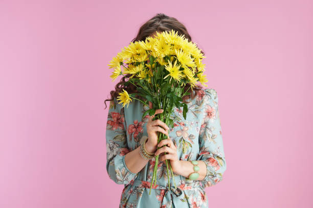 istock woman hiding behind chrysanthemums flowers on pink 1307896205
