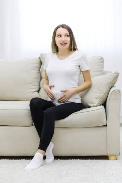 istock Pregnant woman sitting on white sofa. 1307897558