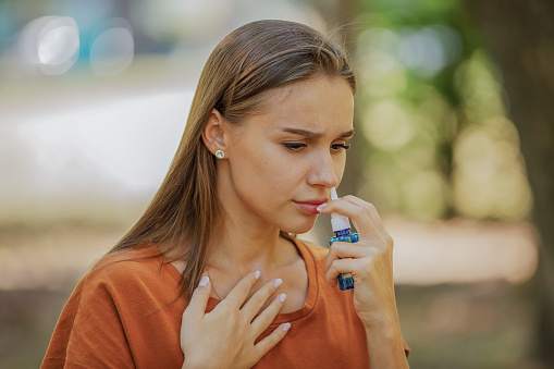 A Woman of Caucasian Ethnicity is Using Nasal Spray Due to the Problems with Nose and Breathing in the Public Park.