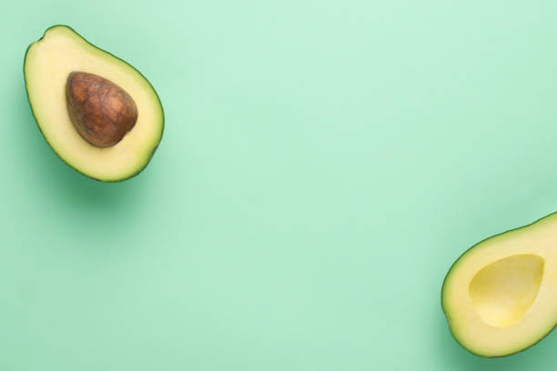 istock Halved avocado on a green background with copy space. 1307902144