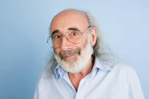 Close-up senior grey-haired man in glasses isolated over light blue background.