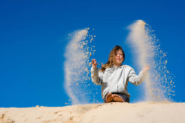 istock cute little girl having fun with sand dunes 1307905874