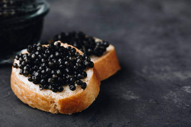 Black caviar sandwiches with butter on dark background Black caviar sandwiches with butter on dark concrete background caviar stock pictures, royalty-free photos & images