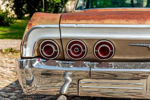 Close up of a beat up and sun bleached classic American car from the sixties in bright sunlight