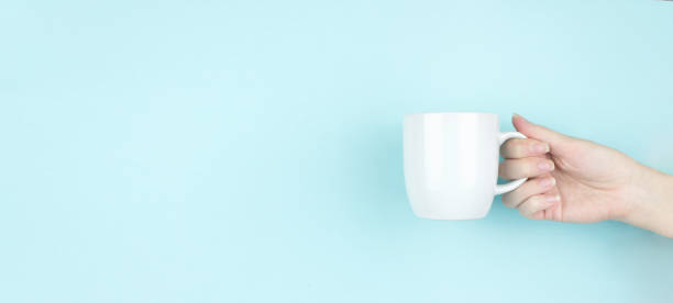 istock Girl hand hold morning coffee cup. Copy space. Blue background. 1307910060
