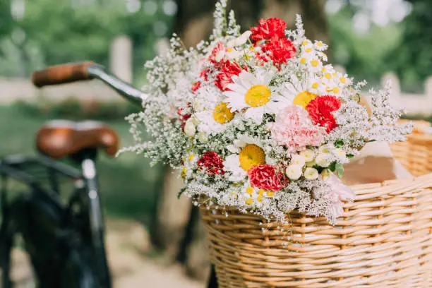 Close up of flowers in a wooden basket on a bicycle.