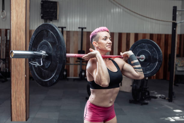donna atletica che tiene in mano un bilanciere nella moderna palestra di cross. allenamento funzionale - crouching barbell weightlifting weight training foto e immagini stock