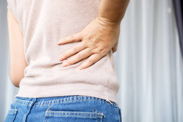 istock woman suffering from lower back pain, hand holding right side back 1307914865