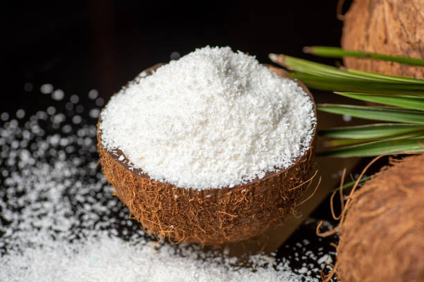 geriebenes kokospulver fällt aus einer kokosnussschale mit kopierraum - powdered coconut stock-fotos und bilder
