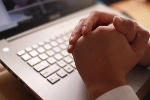istock Businessman hand in pray gesture in front of laptop computer 1307922137