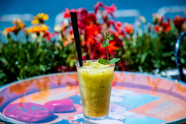 Yellow fruit and rum cocktail mix blended into puree with ice in drinking glass on tray, outdoor cocktail party