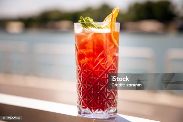 Red Cocktail On The Rocks With Mint Leaf And Orange Peal Stock Photo - Download Image Now