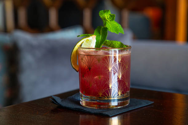 roter cocktail auf den felsen mit minzblatt und limettenpeal auf bartisch - crushed ice freshness red lime stock-fotos und bilder