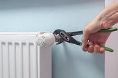Plumber Fixing Radiator With Wrench. Heating radiator with temperature regulator, thermostat.