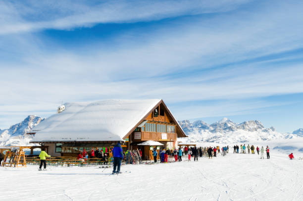 View of a mountain hut in the Dolomites. Lots of skiers on their way to the hut for lunch. stock photo