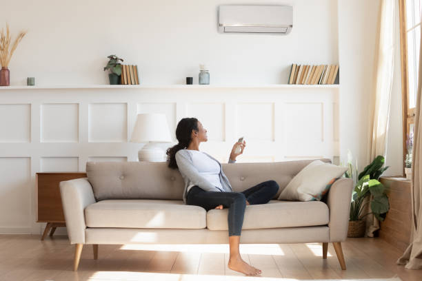istock Biracial woman switch air conditioner with remote 1307926913