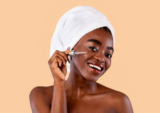 black lady applying moisturizer or hyaluronic acid on face - rebellion aging process facial mask beauty treatment imagens e fotografias de stock