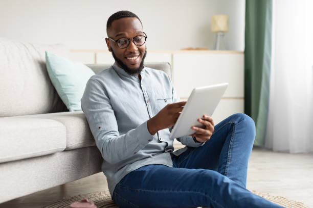 istock Happy African Man Using Tablet Browsing Internet Sitting At Home 1307928453