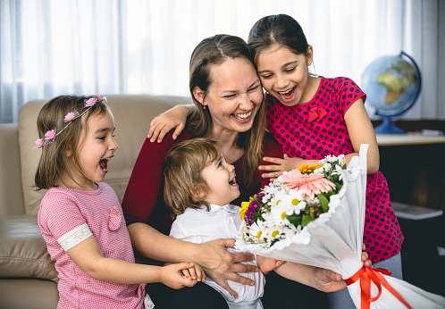 Children Surprising Mother On Mother's day With Bouquet And Greeting Card