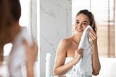 Woman Drying Clean Face With Towel After Washing In Bathroom