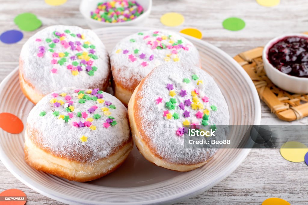 Carnival sprinkled doughnuts and confetti, holiday celebration, baking, top view Colorful carnival doughnuts, holiday celebration baking, top view Jelly Doughnut Stock Photo