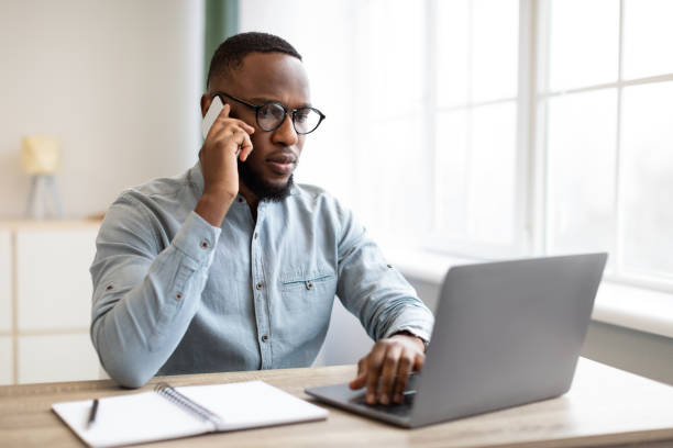 istock Serious Black Businessman Talking On Mobile Phone Sitting At Workplace 1307930642