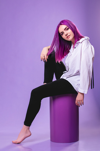 Model girl young beautiful stylish in a white shirt with hair dyed purple on a violet background