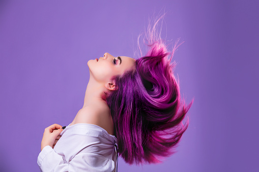 Modelo chica joven hermosa elegante con el pelo teñido de púrpura sobre fondo violeta photo