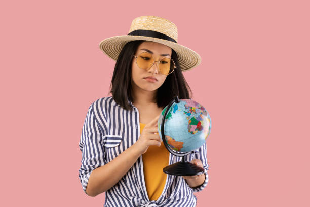 istock Sad Asian Woman Holding Globe, Pointing At Map 1307932031