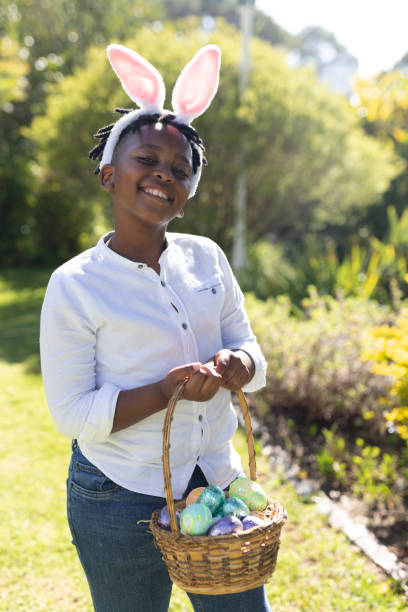 istock Portrait of smiling african american boy holding basket while easter egg hunting 1307932072