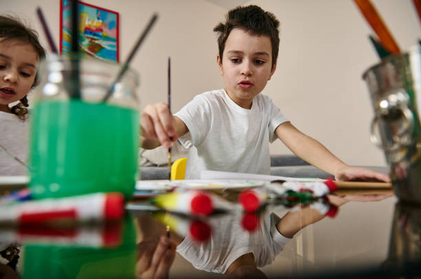 istock Schoolboy performing watercolor painting technique during indoor creativity lesson 1307932191