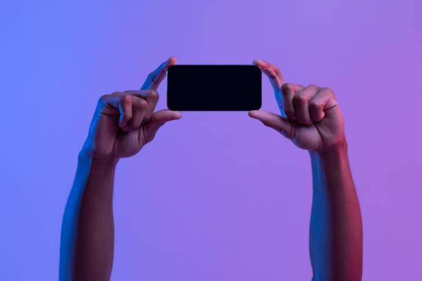 istock Black Male Hands Holding Smartphone With Black Screen In Horizontal Orientation, Mockup 1307932752