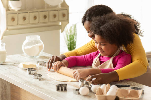 istock Loving Black Mom Teaching Daughter How To Roll Dough, Baking In Kitchen 1307933187