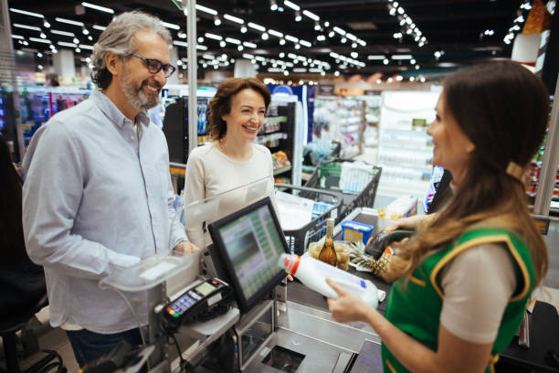 istock Young female cashier scanning products with bar code reader for mature couple 1307933233