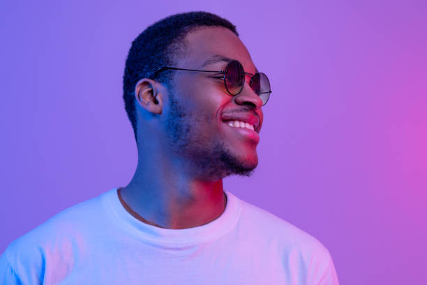 istock Smiling Handsome Black Millennial Guy In Stylish Eyeglasses Posing Under Neon Light 1307933322