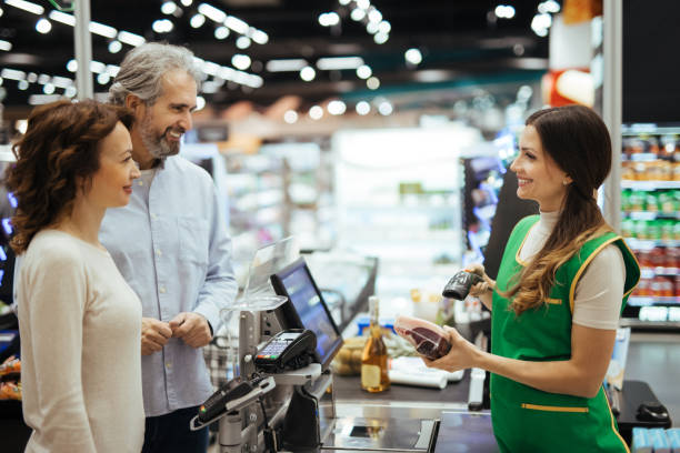 jovens mulheres caixa digitalizando produtos com leitor de código de barras para casal maduro - bar code retail bar code reader food - fotografias e filmes do acervo