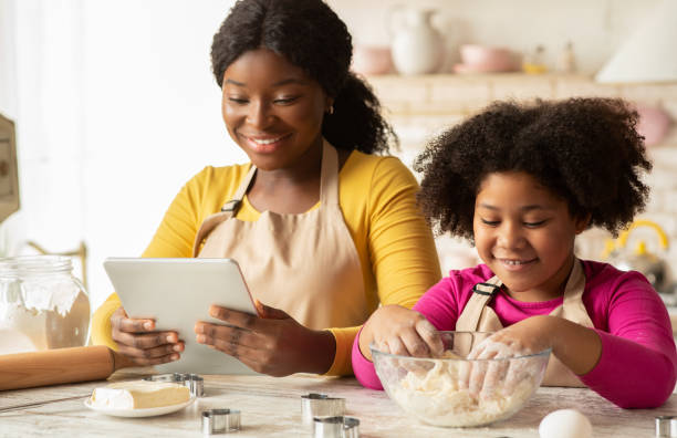 istock Cheerful Black Mom And Daughter Using Digital Tablet In Kitchen, Checking Recipe 1307933485