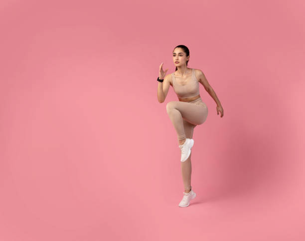 istock Young Woman Doing High Knees Exercise Isolated On Pink Background 1307933578