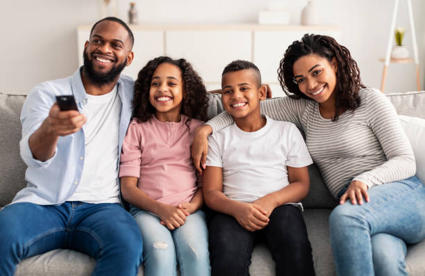 istock Happy young family watching television sitting on sofa 1307934265