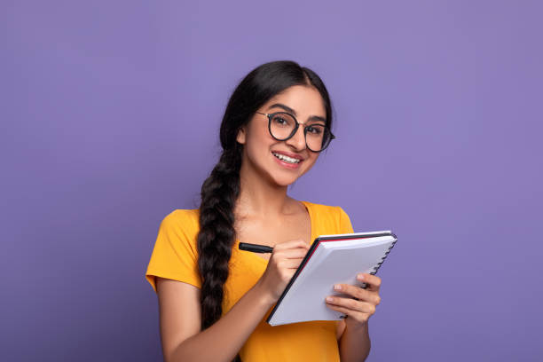 istock Indian woman holding pen writing in notebook at studio 1307934272